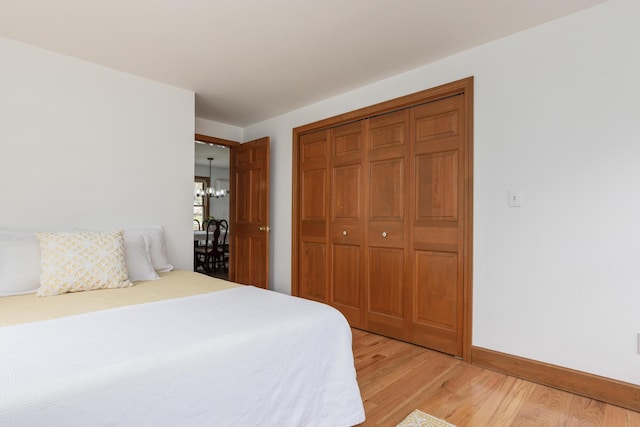 784 Ocean Ave, Portland, ME 04103 - bedroom featuring light wood-style flooring, a closet, baseboards, and a chandelier