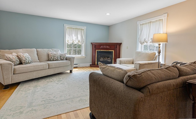 74 Town Farm Rd, Hampden, ME 04444 - living room with light wood-style flooring, a baseboard heating unit, a glass covered fireplace, recessed lighting, and baseboards