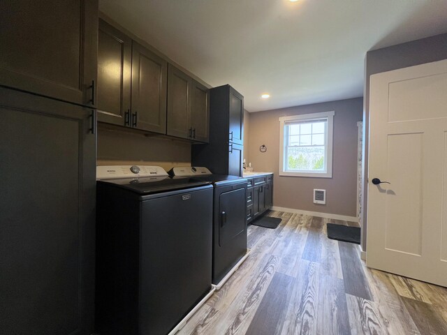 99 St John Rd, Fort Kent, ME 04743 - clothes washing area with independent washer and dryer, baseboards, visible vents, light wood-style floors, and cabinet space