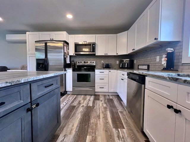 99 St John Rd, Fort Kent, ME 04743 - kitchen featuring a wall unit AC, tasteful backsplash, stainless steel appliances, white cabinets, and dark wood-style floors
