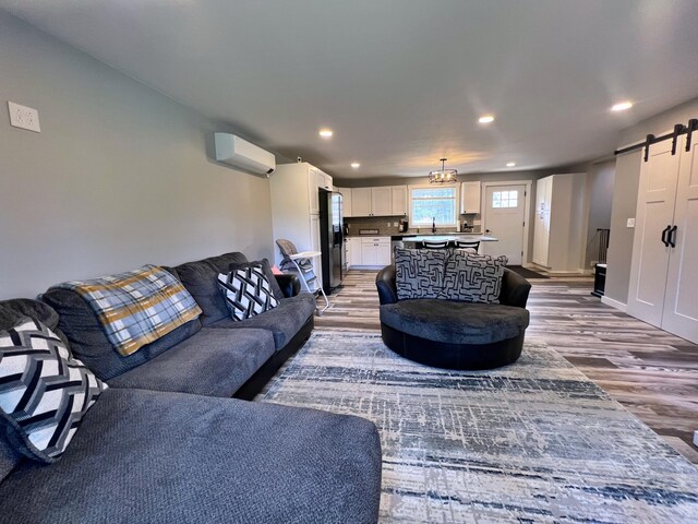 99 St John Rd, Fort Kent, ME 04743 - living room featuring wood finished floors, a wall unit AC, a barn door, baseboards, and recessed lighting