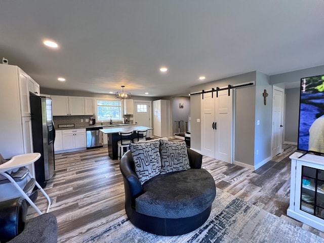 99 St John Rd, Fort Kent, ME 04743 - living room with a chandelier, wood finished floors, a barn door, and recessed lighting