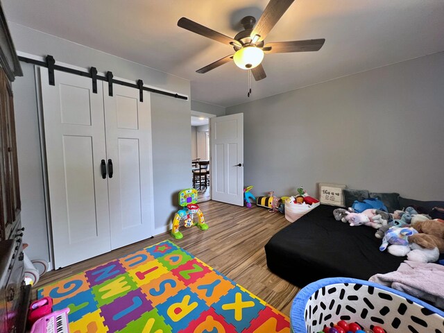99 St John Rd, Fort Kent, ME 04743 - bedroom featuring a ceiling fan, a barn door, and wood finished floors