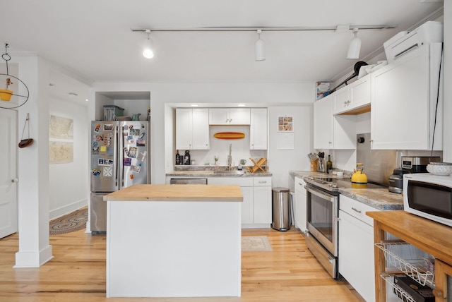 17 Pine St Unit 3, Portland, ME 04102 - kitchen featuring stainless steel appliances, a center island, track lighting, light wood-style flooring, and white cabinets