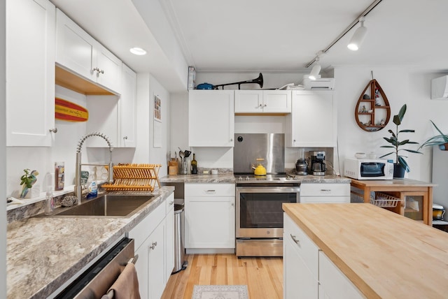17 Pine St Unit 3, Portland, ME 04102 - kitchen with stainless steel appliances, a sink, white cabinetry, light wood-type flooring, and butcher block countertops