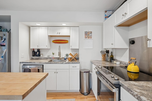 17 Pine St Unit 3, Portland, ME 04102 - kitchen featuring stainless steel appliances, a sink, white cabinetry, light wood finished floors, and ornamental molding