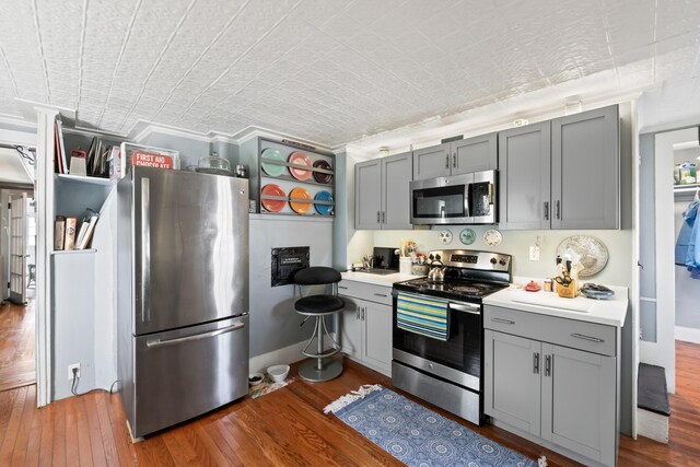 98 Main St, Winthrop, ME 04364 - kitchen featuring appliances with stainless steel finishes, gray cabinets, wood finished floors, light countertops, and crown molding