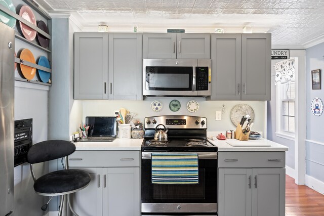 98 Main St, Winthrop, ME 04364 - kitchen featuring appliances with stainless steel finishes, gray cabinets, ornamental molding, an ornate ceiling, and wood finished floors