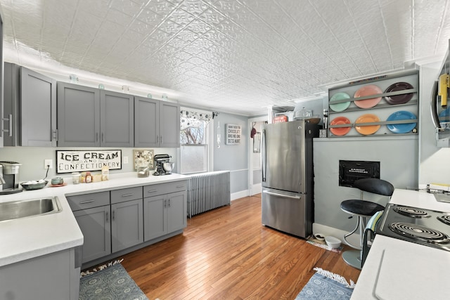 98 Main St, Winthrop, ME 04364 - kitchen with freestanding refrigerator, radiator, gray cabinets, light wood-style flooring, and light countertops