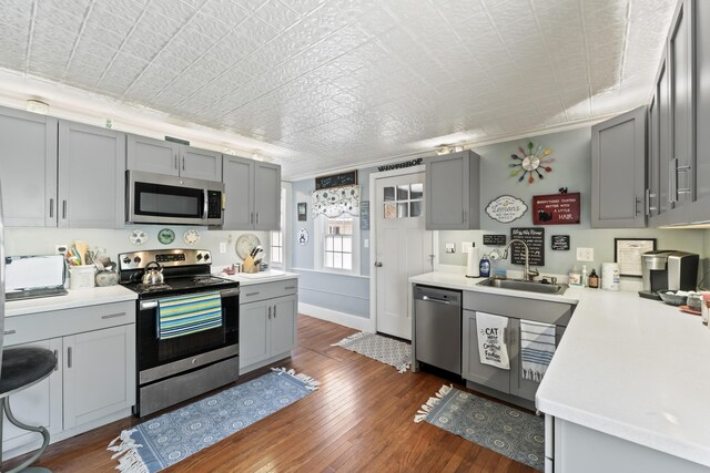 98 Main St, Winthrop, ME 04364 - kitchen featuring stainless steel appliances, gray cabinetry, a sink, and ornamental molding