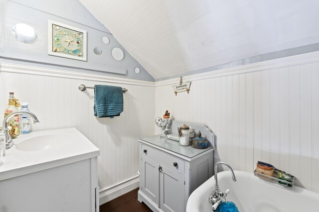 98 Main St, Winthrop, ME 04364 - bathroom featuring vaulted ceiling, a bathtub, a wainscoted wall, and vanity