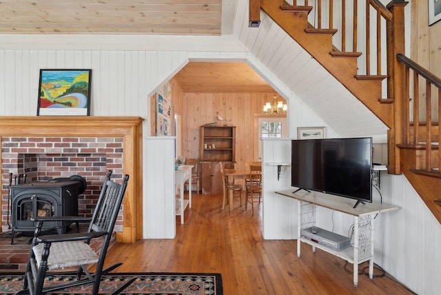60 Grove St, Wells, ME 04090 - living area with hardwood / wood-style flooring, a wood stove, stairway, wooden walls, and a notable chandelier