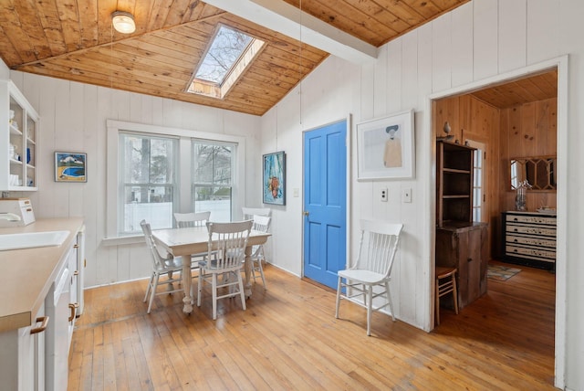 60 Grove St, Wells, ME 04090 - dining space featuring wooden walls, wood ceiling, vaulted ceiling with skylight, and light wood-style floors