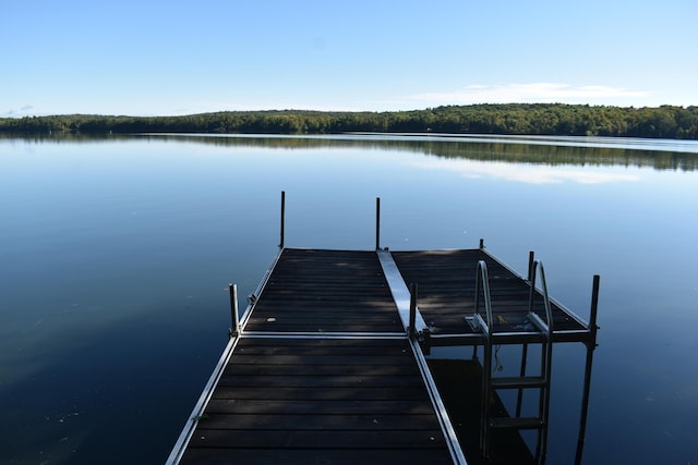 view of dock featuring a wooded view and a water view