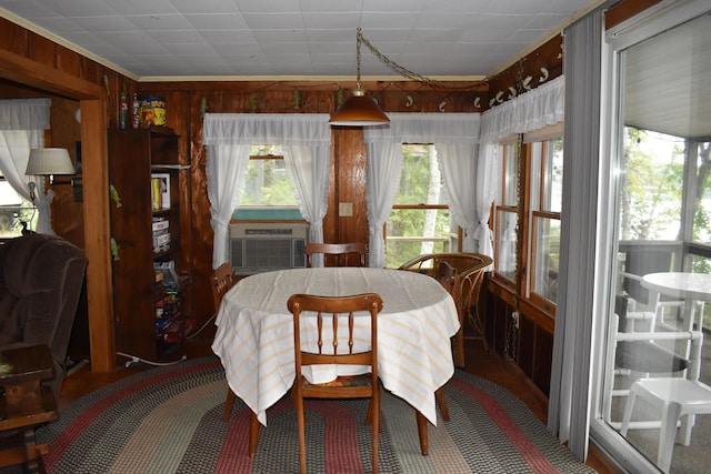 dining area with cooling unit, wooden walls, and crown molding