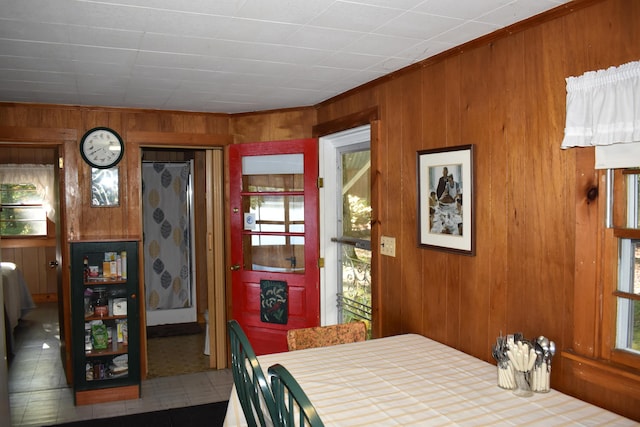 dining space with ornamental molding and wood walls