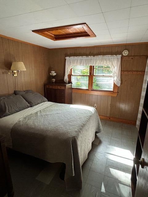 bedroom featuring tile patterned floors, attic access, and wood walls