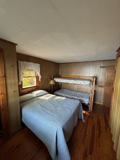 bedroom featuring dark wood finished floors and wood walls