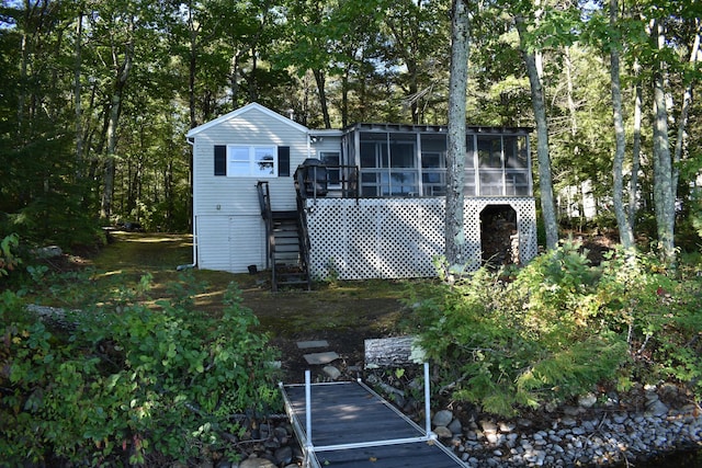 back of property with a sunroom and stairway