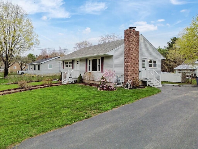 view of front of house featuring a front lawn, a shingled roof, and a chimney