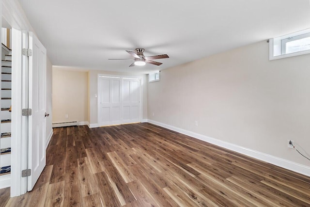 unfurnished bedroom featuring a baseboard heating unit, baseboards, a closet, and wood finished floors