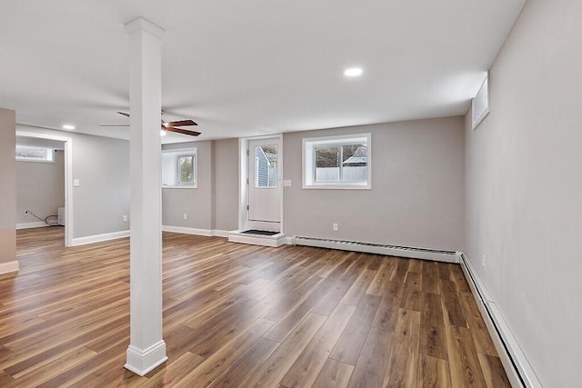 basement featuring baseboard heating, a baseboard heating unit, baseboards, ceiling fan, and wood finished floors