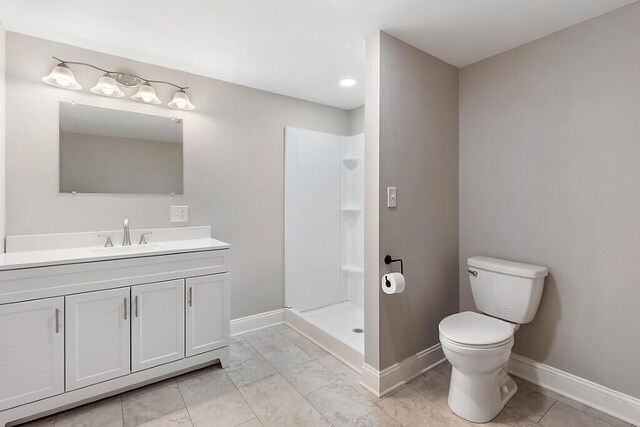 bathroom with toilet, baseboards, vanity, and a stall shower