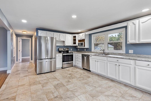 kitchen featuring glass insert cabinets, a sink, white cabinets, appliances with stainless steel finishes, and recessed lighting
