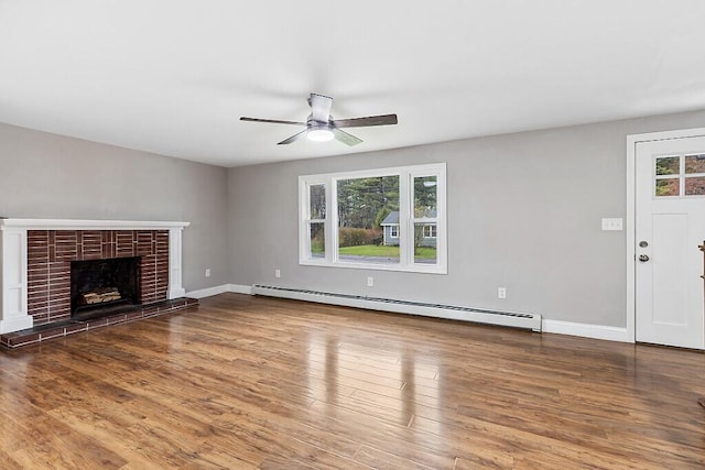 unfurnished living room featuring a ceiling fan, wood finished floors, baseboard heating, and a fireplace