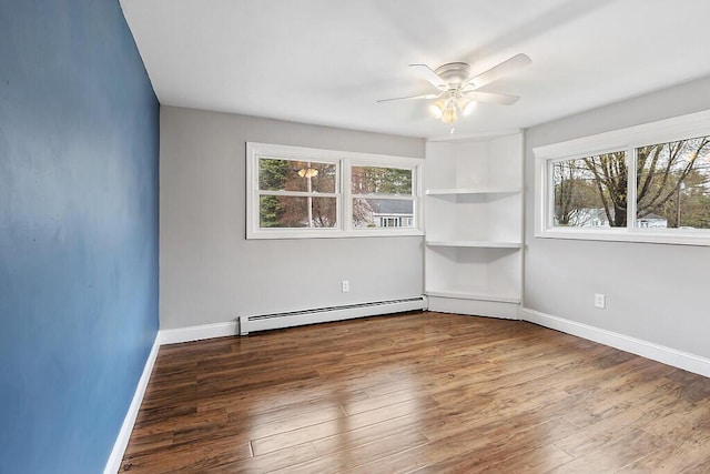 spare room featuring a wealth of natural light, a baseboard radiator, ceiling fan, and wood finished floors