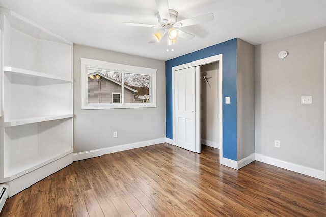unfurnished bedroom featuring a closet, wood finished floors, baseboards, and ceiling fan