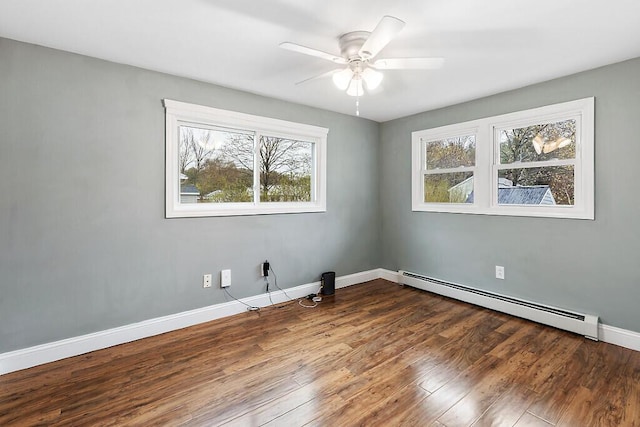 spare room featuring baseboards, baseboard heating, a ceiling fan, and wood finished floors