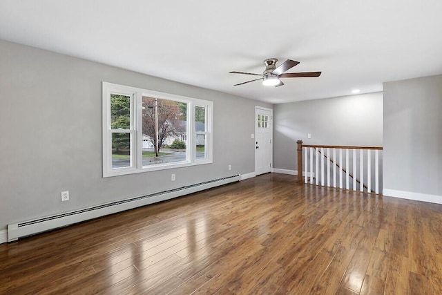 empty room with a baseboard heating unit, baseboards, ceiling fan, and wood finished floors