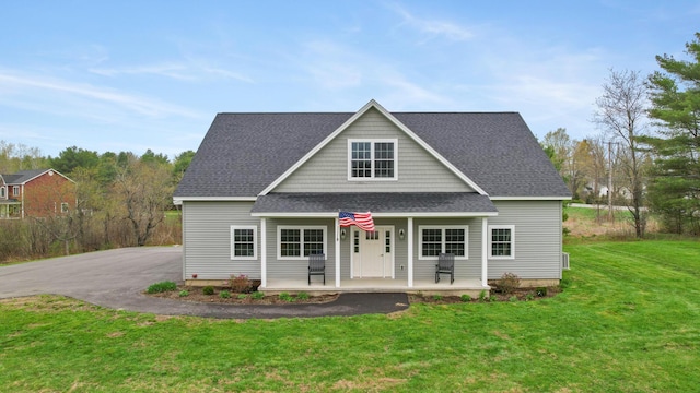 view of front of house with covered porch, a shingled roof, and a front lawn
