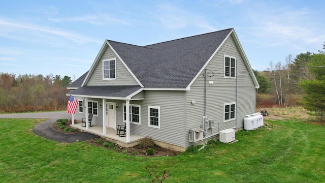 back of house featuring a porch, roof with shingles, and a yard