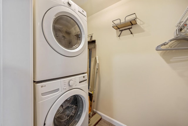 clothes washing area featuring stacked washer / dryer and baseboards