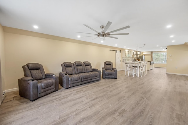 living area featuring a barn door, recessed lighting, light wood-style floors, baseboards, and a ceiling fan
