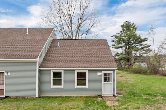 back of property featuring a shingled roof and a lawn