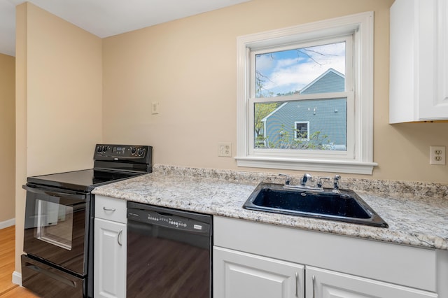 kitchen featuring white cabinetry, black appliances, a sink, and wood finished floors