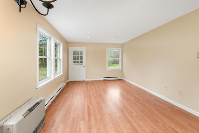 interior space featuring a baseboard radiator, light wood finished floors, baseboards, and baseboard heating