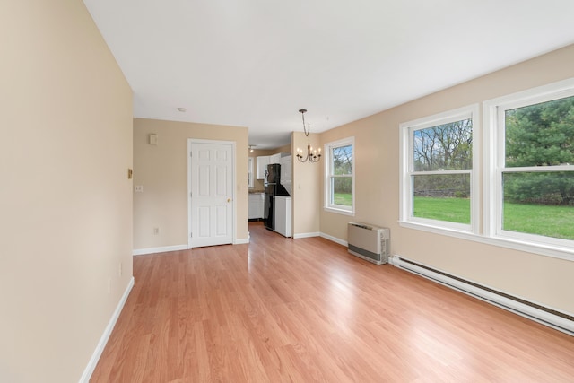 unfurnished dining area with light wood finished floors, an inviting chandelier, baseboards, and a baseboard radiator