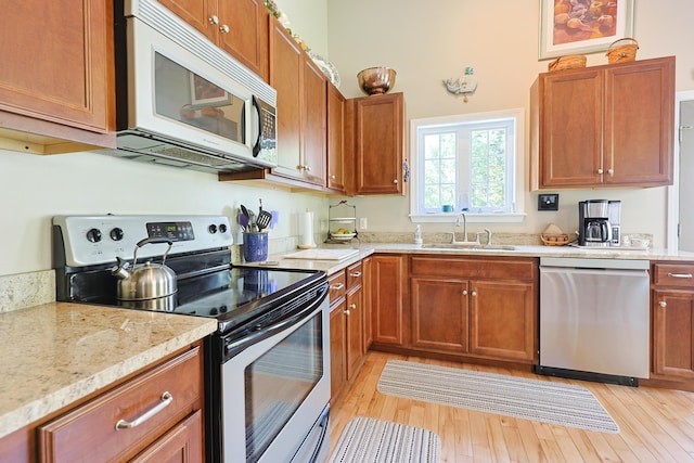8 Codys Way, Bridgton, ME 04009 - kitchen featuring appliances with stainless steel finishes, a sink, light wood-type flooring, brown cabinetry, and light stone countertops