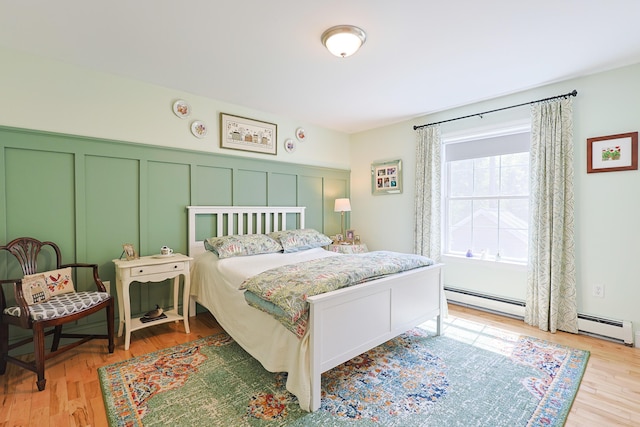 8 Codys Way, Bridgton, ME 04009 - bedroom with a decorative wall, a baseboard radiator, light wood-type flooring, and a wainscoted wall