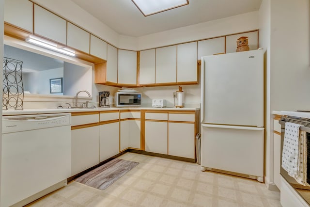 kitchen with white appliances, light countertops, a sink, light floors, and white cabinetry
