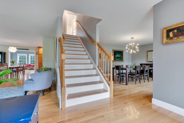 staircase featuring a chandelier, wood finished floors, and baseboards