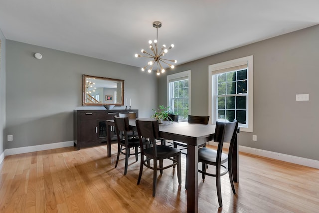 dining space with light wood finished floors, a chandelier, and baseboards