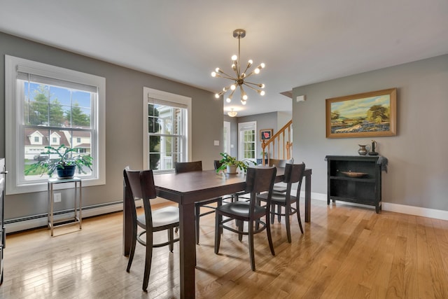 dining space with a chandelier, plenty of natural light, light wood-style flooring, and a baseboard radiator