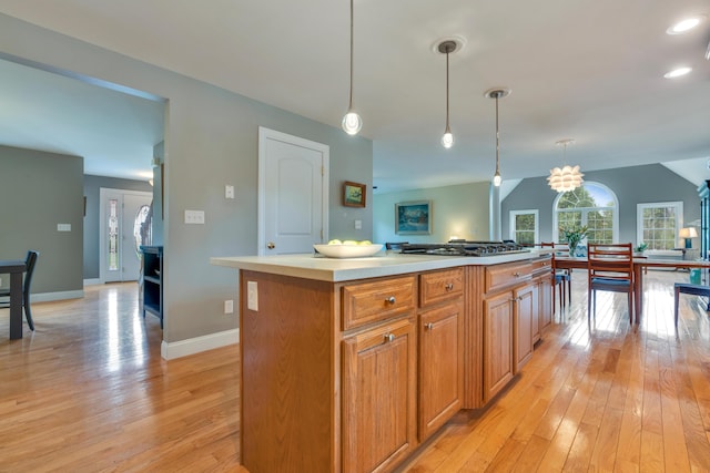 kitchen with light wood finished floors, baseboards, light countertops, pendant lighting, and a kitchen island