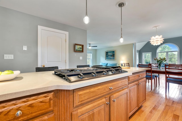 kitchen with stainless steel gas stovetop, light countertops, light wood-style flooring, hanging light fixtures, and a ceiling fan