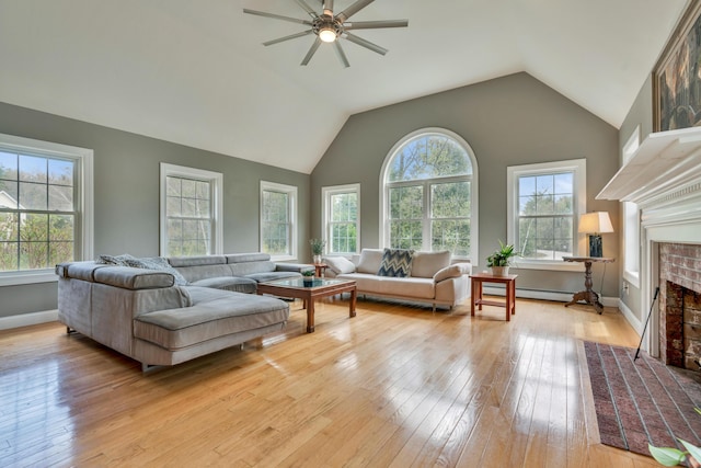 living area featuring light wood-style floors, a fireplace, a ceiling fan, lofted ceiling, and baseboard heating